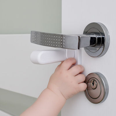 bloque porte bebe blanc main adulte installe poignée levier serrure porte bois