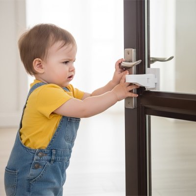 bloque porte blanc bébé jaune salopette essaie ouvrir porte vitrée marron poignée levier